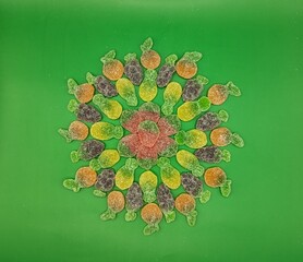 Mandala made with sweet fruit gummy on green background, centered