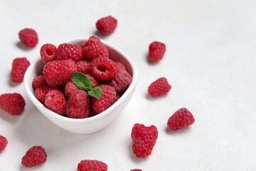 Bowl with fresh raspberry and mint on light background, closeup