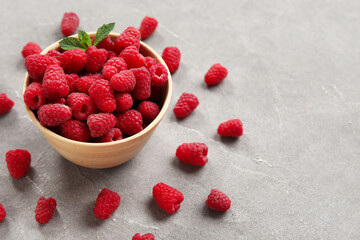 Bowl with fresh raspberry and mint on grey background, closeup