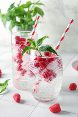 Glasses of fresh raspberry lemonade with mint on white tile table