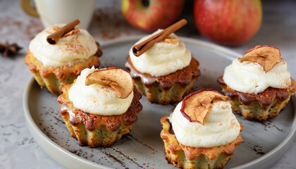 Apple cupcakes with cream cheese frosting decorated with dried apple slices and cinnamon powder. Autumn festive dessert. Homemade tasty pastry on ceramic cake plate. Close up food.