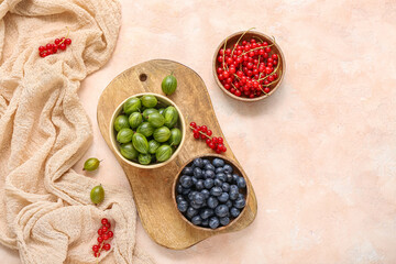 Bowls with fresh berries on beige background