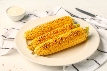 Plate with tasty grilled corn cobs and sauce on white background
