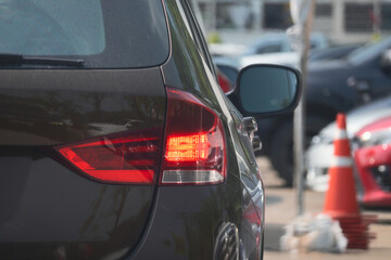 red tail light of brown car in large asphalt parking lot, transportation industry