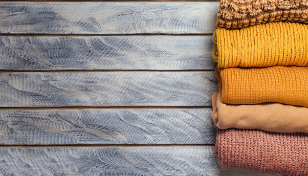 knitted sweaters on a wooden background, space for text	
