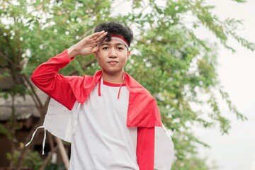 Indonesian men celebrate Indonesian independence day on 17 August by holding the Indonesian flag at...