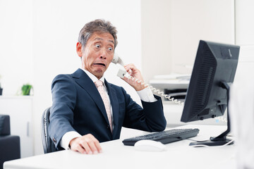 電話で驚く管理職の男性
