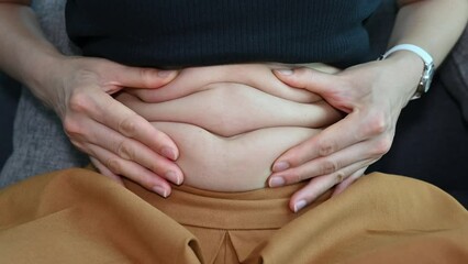 Close up of woman touching and playing her fat belly after finishing eating.
