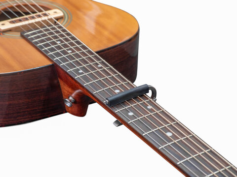 Capo on the Acoustic guitar neck , capro made from aluminium, Selective focus at capo, whtie background.