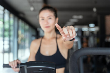 Asian woen  exercising bitch on exercise machine pointing forward with a smile.