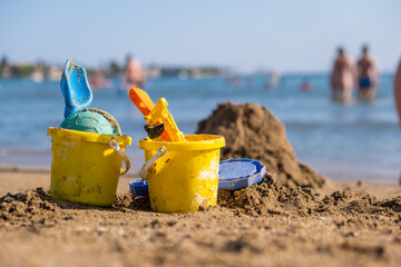 Children's beach toys - buckets, spade and shovel on sand on a sunny day. Bright toys on the...
