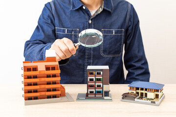 住宅模型を虫眼鏡で観察する男性