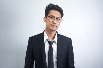 Indoor picture of young business man in glasses pictured isolated on white background looking straight at camera, showing confidence and providing stability for employees