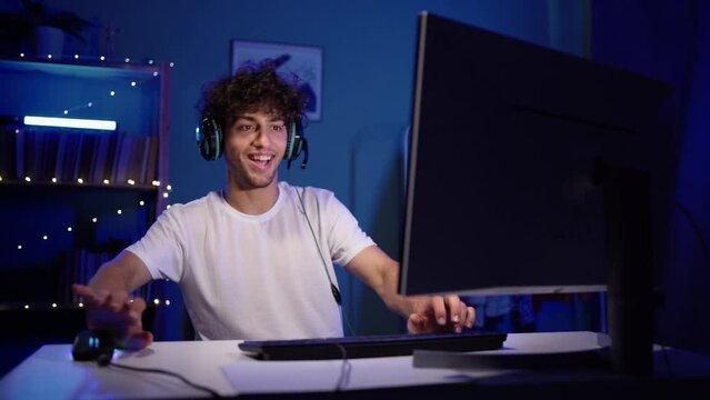 Professional arabic gamer playing online video game on his personal computer. Blue neon led room.