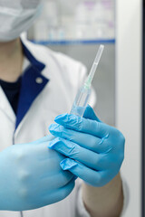 doctor's hands in blue sterile gloves hold an injection syringe with medicine