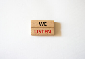 We listen symbol. Wooden blocks with words We listen. Beautiful white background. Business and We listen concept. Copy space.