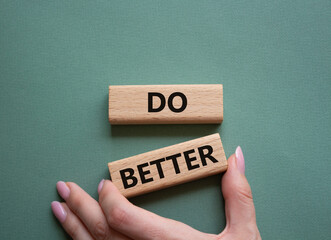 Do better symbol. Wooden blocks with words Do better. Beautiful grey green background. Businessman hand. Business and Do better concept. Copy space.