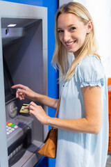 Fototapeta na wymiar beautiful young blonde woman uses card in cash machine