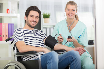 young attractive nurse checking the disabled mans blood pressure