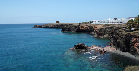 Fototapeta na wymiar Old Napolionic Fort and hotel on cliff top at Playa Blanca Lanzarote Spain.