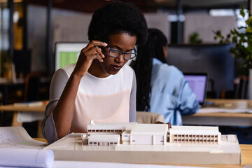 African american female architect with afro working on model in office