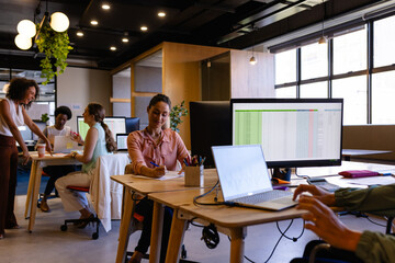 Diverse casual businesswomen working on computers at desks in office