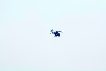 Combat helicopter is flying against isolated blue sky. Combat helicopter attack enemy.