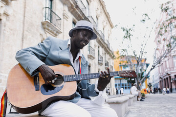 Black Man musician playing guitar on the street in La Havana in Latin America, Afro american and...