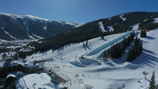 Drone aerial Copper Mountain winter ski snowboard resort half pipe training practice tricks competition Colorado early morning sunlight fresh snow unique birds eye cinematic forward pan up motion 4k