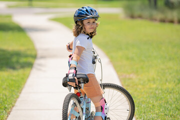 Child in safety helmet riding bike. Boy riding bike wearing a helmet outside. Child in safety helmet riding bike. Little kid boy learns to ride a bike. Kid on bicycle. Happy child in helmet riding a