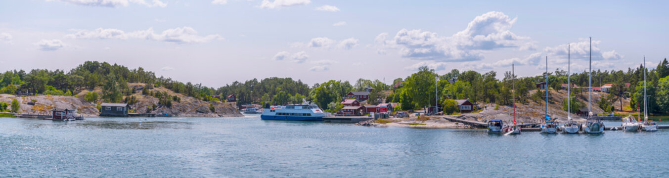 Island, skerries, islet, in the archipelago,  houses, boat sheeds, jetties. Old steam passenger and sail boat passing the island M&ouml;ja on the bay , a sunny summer day in Stockholm