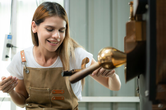 Portrait of a young woman working with a coffee roaster machine