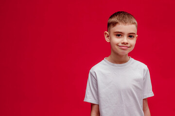 Portrait of a beautiful 8-year-old boy on a red background