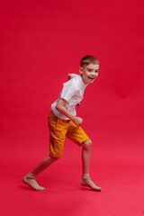 Cheerful boy dancing on a red background