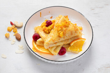 Crepe suzette with orange sauce and raspberry for a delicious breakfast.