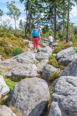 Two tourists walsking on the red hiking trail between the rock towns of Błędne Skały and Szczeliniec Wielki in the Central Sudetes in the Stolowe Mountains (Poland) © IwoiWo
