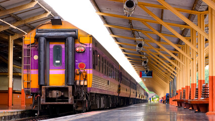 The old multicolored passenger diesel train waiting for passengers at the platform of Chiang Mai train station, Thailand. low angle and perspective side view
