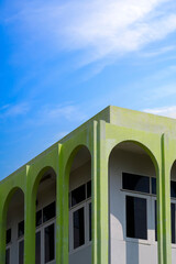 Low angle and perspective view of the old vintage green residential building with arch sunshade wall against blue sky background in vertical frame