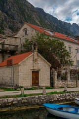 Christian church with a bell tower on the shore of the Bay of Kotor in Dobrota, a boat in the water