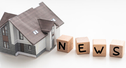 Real estate news symbol. Wooden blocks form the words 'Real estate news', miniature house, wooden table. Beautiful white background, copy space. Business and real estate news concept.
