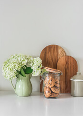 Minimalist kitchen interior - a bouquet of hydrangeas in a vintage ceramic jug, oak cutting boards, cookies in a glass jar. Cozy home