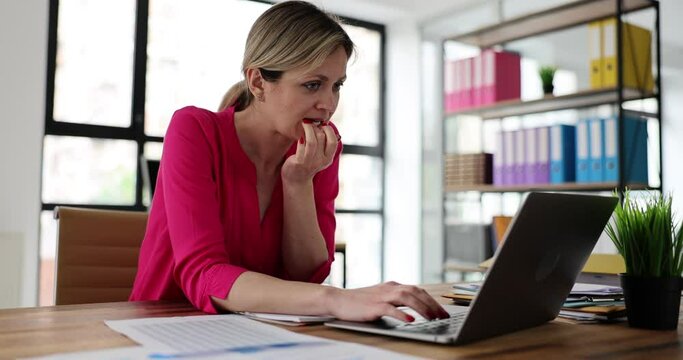 Anxious stressed woman biting nails reading from computer screen in office. Frustrated beautiful professional woman gnawing at work