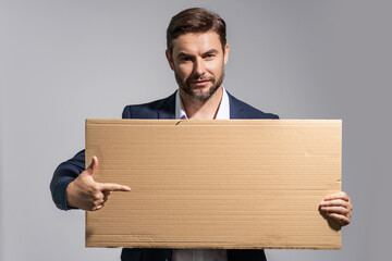 Handsome middle aged man with blank placard. Demonstrating copy space for your text or design. Man showing empty advertisement board on studio background. Blank placard, signboard for ad.