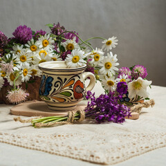 A cup of coffee and spring wildflowers on a white tablecloth.