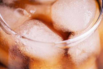 Background of brown soda, cold tea or coffee with ice cubes and bubbles, macro. Fresh cold sweet...