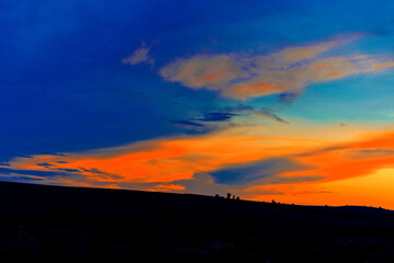 The beautiful sunset sun is setting over the horizon. Golden rays. In the twilight of summer time. Beautiful sky with clouds colored by the sun. Scene of the setting sun. Landscape in the park.	