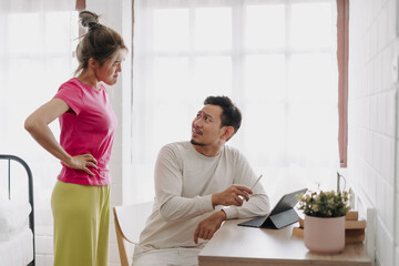 Fototapeta premium Asian wife asking husband to stop working and watching with computer tablet.