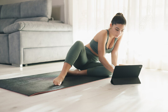 Sportswoman using tablet PC during online yoga lesson