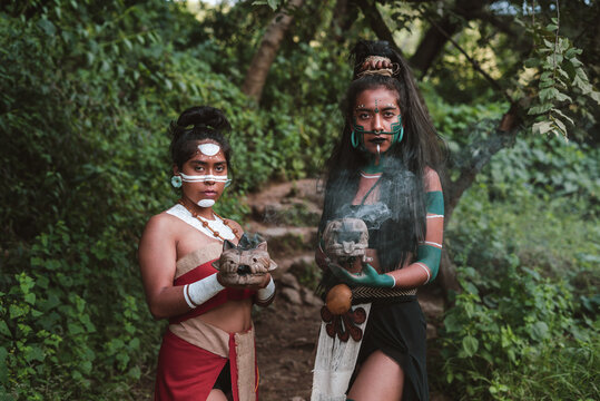 Serious women with smoky carved weapon in forest