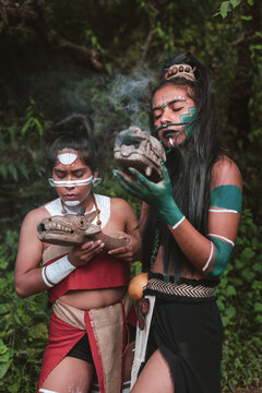 Two indigenous women with fire stones performing smoke ritual